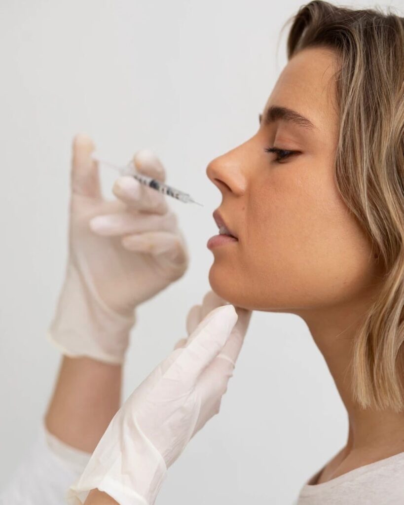 Patient demonstrating lip filler treatment process with natural enhancement results in professional clinic setting.