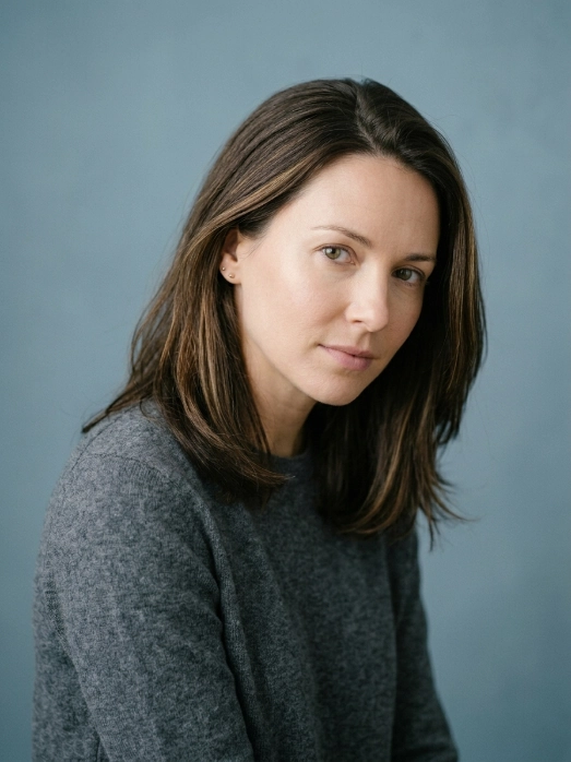 A woman with a calm thoughtful expression against a dusty blue background, reflecting the Juvelook treatment process.