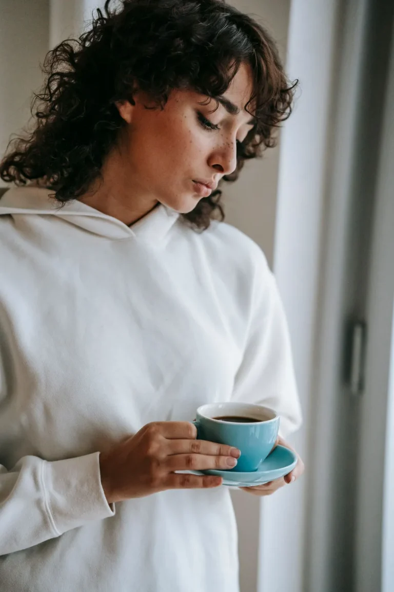 Woman holding a cup of coffee before a lip filler appointment, illustrating pre-treatment caffeine restrictions