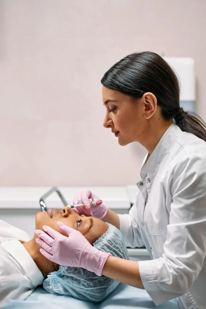 Cosmetic injector assessing nasal anatomy before liquid nose job procedure to reduce treatment risks.