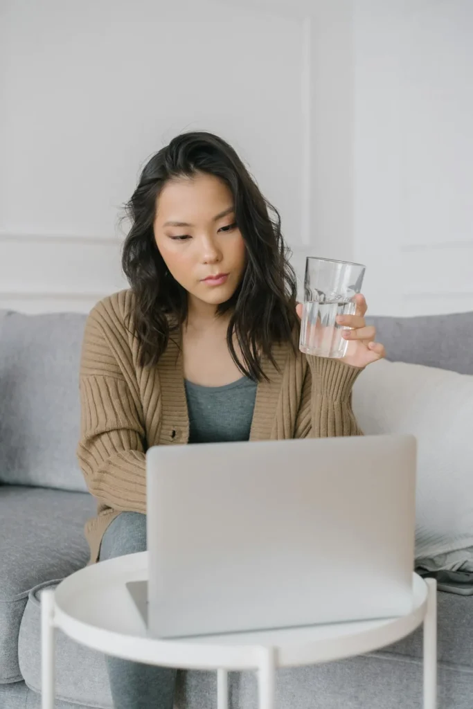 Woman drinking water and reviewing pre-treatment instructions before lip filler appointment
