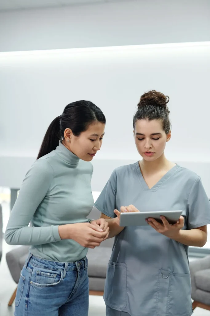 Aesthetic practitioner examining the patient's nose during a non-surgical rhinoplasty consultation, discussing possible complications.