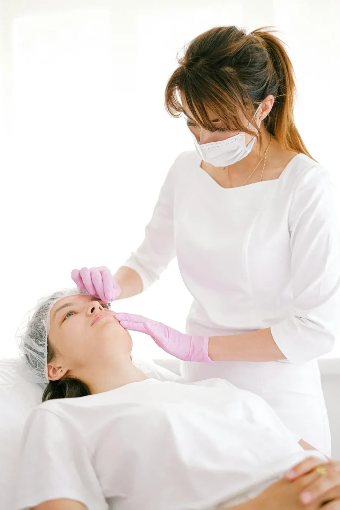 Medical professional assessing skin discolouration and blanching associated with vascular occlusion after facial fillers.