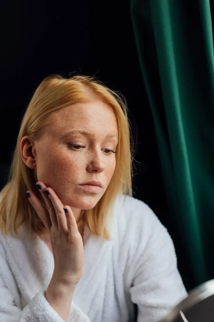 Close-up of a woman touching her cheek with mild facial swelling after cosmetic filler treatment before air travel