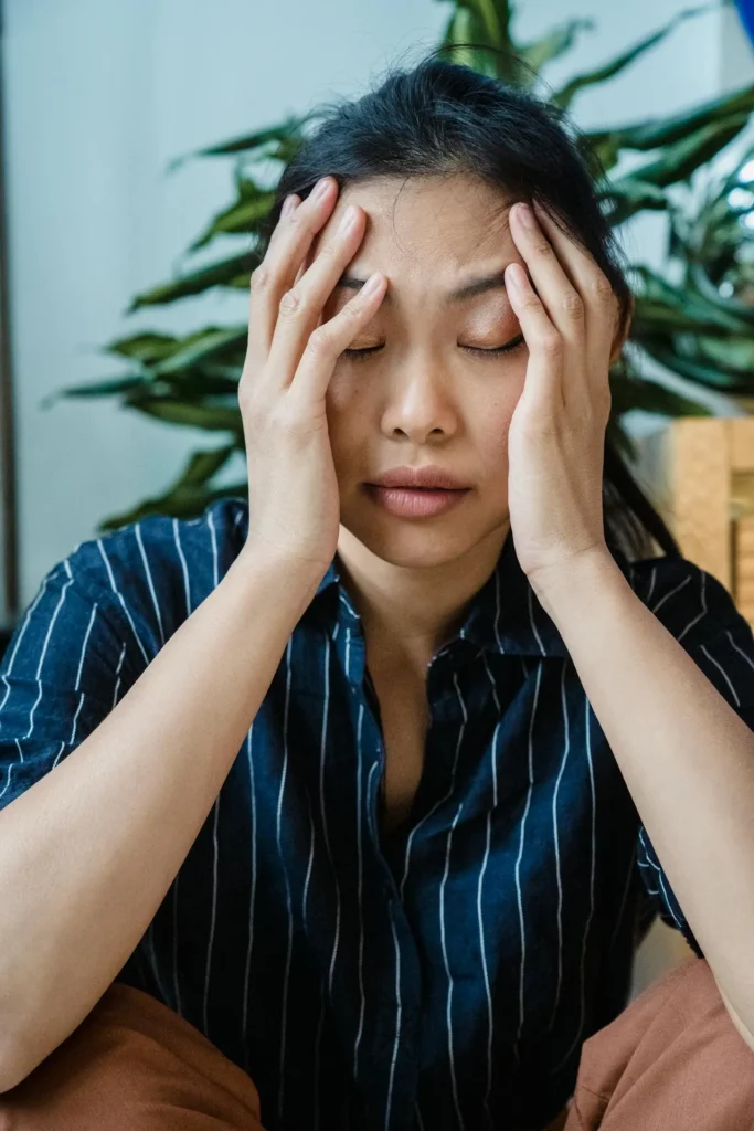 Woman holding forehead gently, showing discomfort after cosmetic injection treatment.