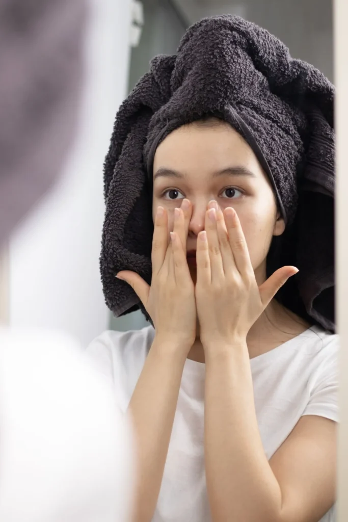 Woman examining facial profile in mirror as cosmetic treatment results gradually fade over time