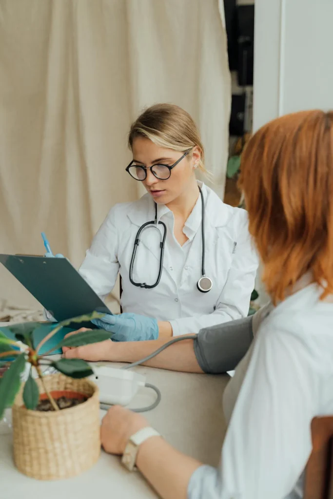 Medical professional examining patient and discussing symptoms during follow-up consultation in clinical environment.