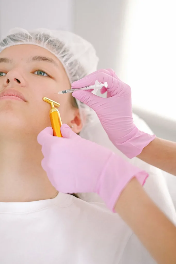 Practitioner performing a jawline filler injection using a syringe during contouring treatment