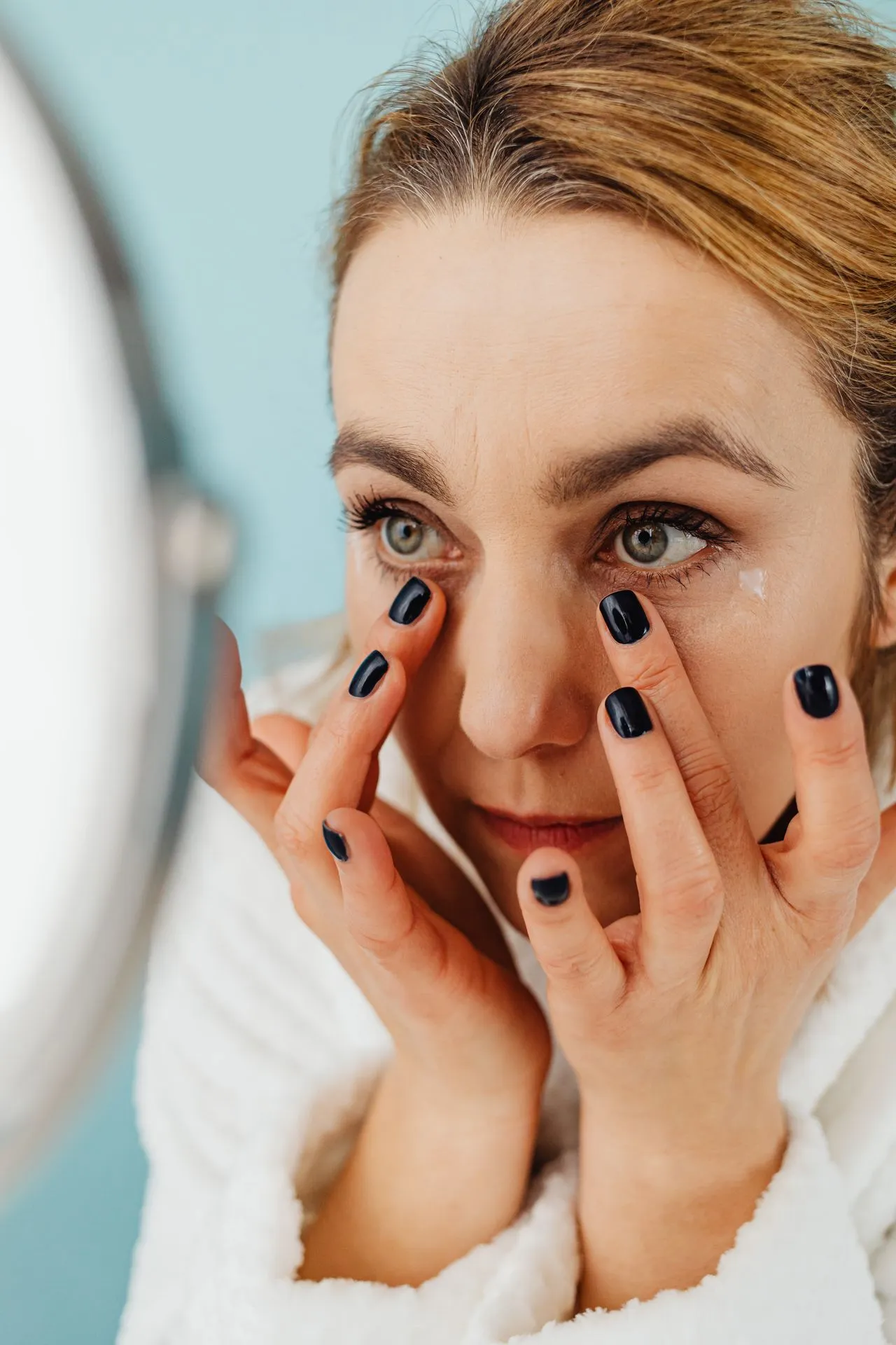 Woman examining under-eye area before tear trough filler treatment